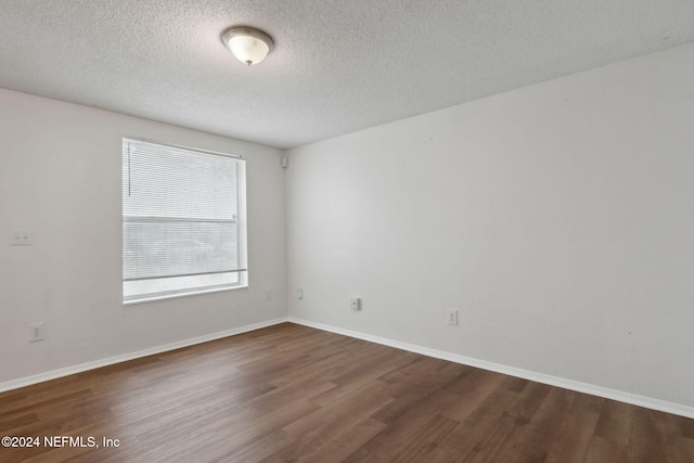 spare room featuring dark hardwood / wood-style flooring and a textured ceiling