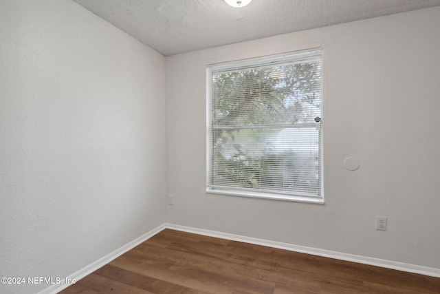 unfurnished room with plenty of natural light, hardwood / wood-style floors, and a textured ceiling