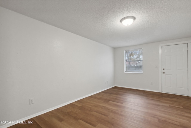 unfurnished room with hardwood / wood-style floors and a textured ceiling