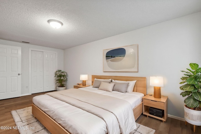 bedroom with a closet, dark hardwood / wood-style flooring, and a textured ceiling