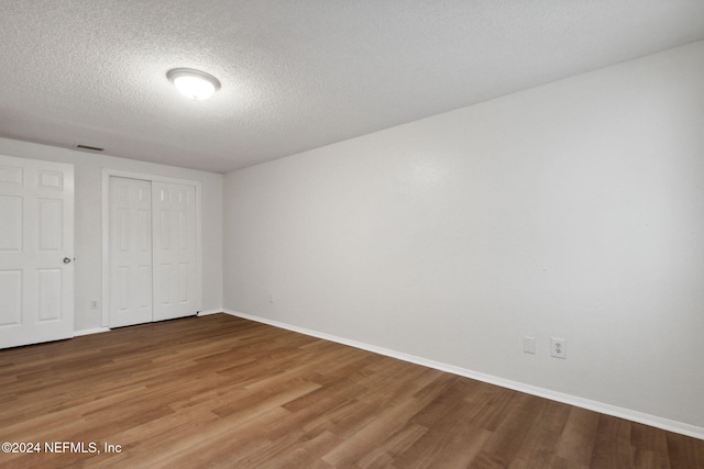 unfurnished bedroom with wood-type flooring, a textured ceiling, and a closet