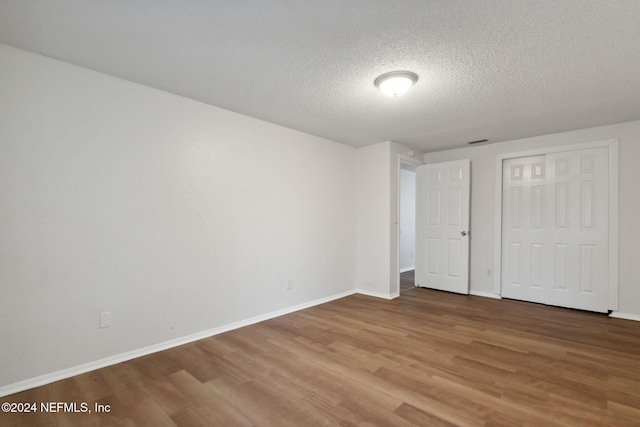 unfurnished bedroom featuring wood-type flooring, a textured ceiling, and a closet