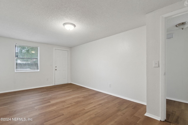 empty room featuring wood-type flooring and a textured ceiling