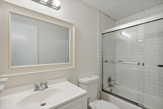 full bathroom with enclosed tub / shower combo, vanity, and toilet