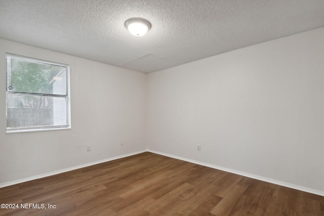 spare room with a textured ceiling and dark hardwood / wood-style flooring