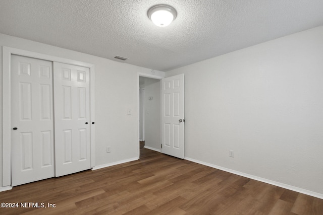 unfurnished bedroom with wood-type flooring, a closet, and a textured ceiling