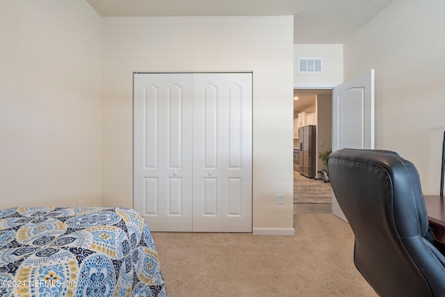 bedroom with stainless steel fridge with ice dispenser, light carpet, and a closet