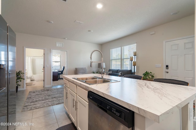 kitchen with white cabinetry, sink, stainless steel appliances, a center island with sink, and light tile patterned flooring