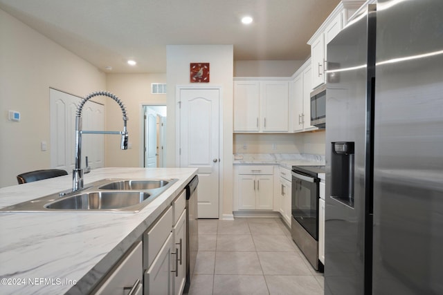 kitchen with sink, white cabinets, stainless steel appliances, and light tile patterned floors