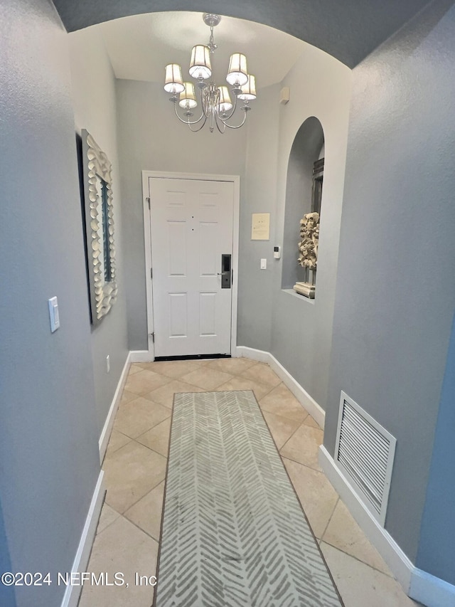 doorway with a notable chandelier and light tile patterned floors