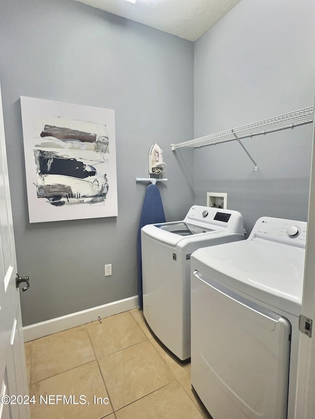 laundry area with washer and dryer and light tile patterned floors