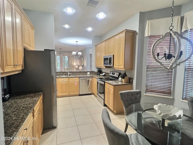 kitchen with appliances with stainless steel finishes, dark stone counters, sink, an inviting chandelier, and hanging light fixtures