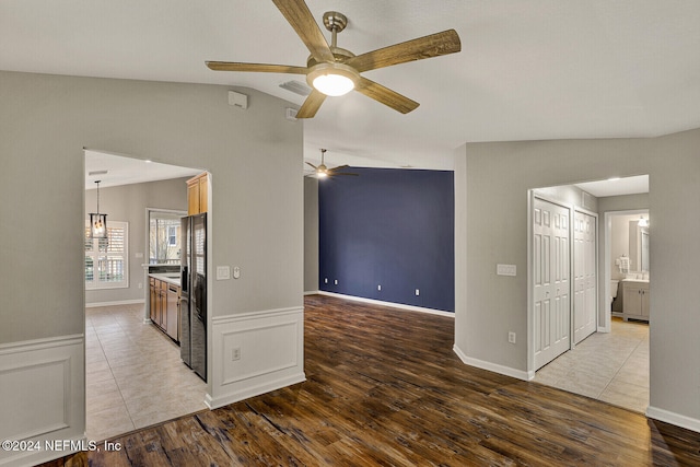 interior space with light hardwood / wood-style floors, stainless steel refrigerator with ice dispenser, and vaulted ceiling