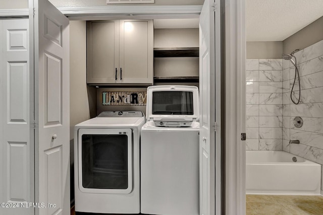 laundry area featuring cabinets, light tile patterned floors, a textured ceiling, and washer and dryer