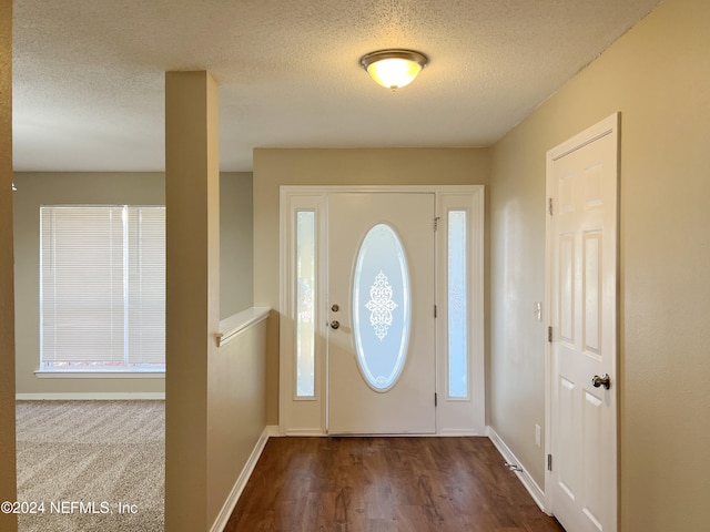 foyer with dark carpet and a textured ceiling