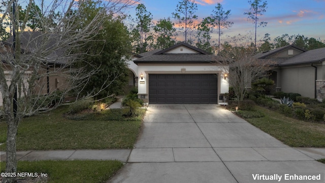 ranch-style house with a garage, concrete driveway, a lawn, roof with shingles, and stucco siding