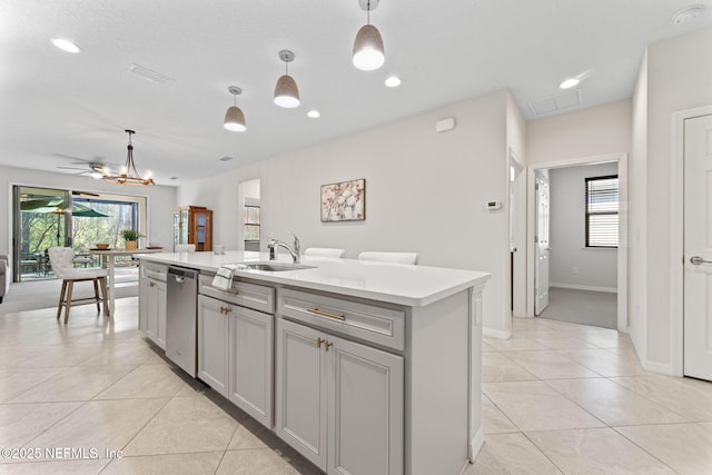 kitchen with pendant lighting, a kitchen island with sink, sink, stainless steel dishwasher, and gray cabinets