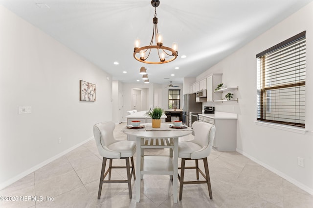 dining space featuring ceiling fan with notable chandelier and light tile patterned flooring