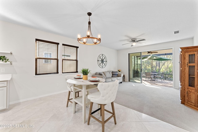 carpeted dining space featuring ceiling fan with notable chandelier