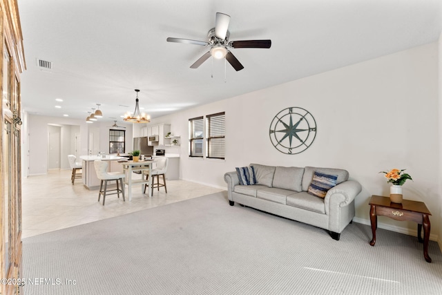 living room featuring ceiling fan with notable chandelier and light tile patterned floors