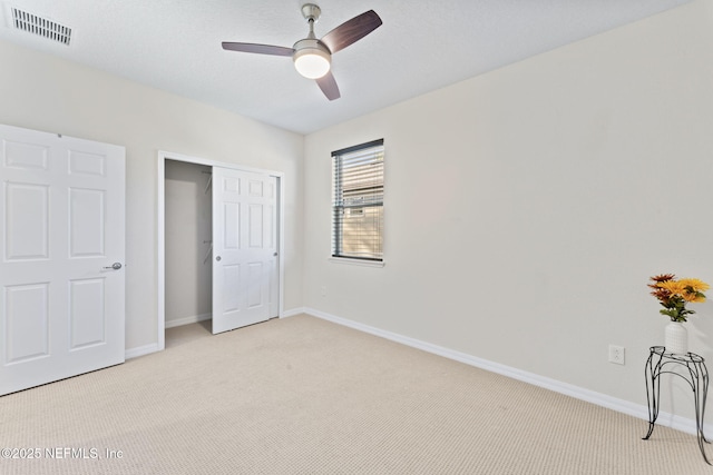 unfurnished bedroom with ceiling fan, light colored carpet, and a closet