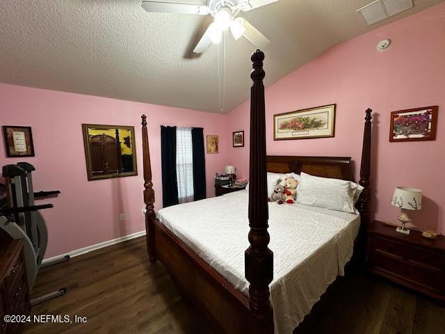 bedroom with a textured ceiling, ceiling fan, lofted ceiling, and dark wood-type flooring