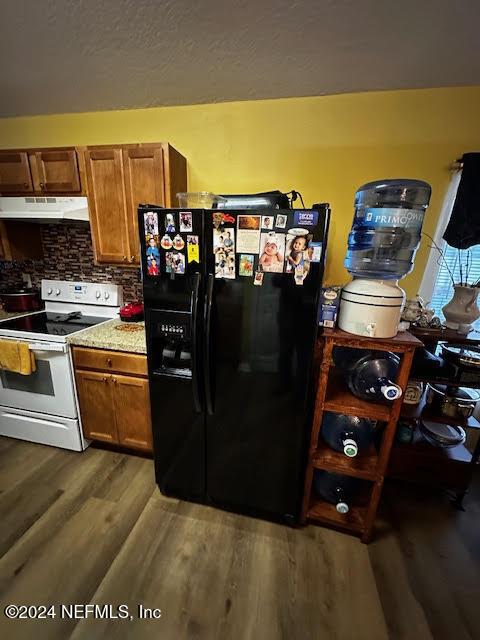 kitchen with backsplash, ventilation hood, white range, dark hardwood / wood-style floors, and black fridge with ice dispenser