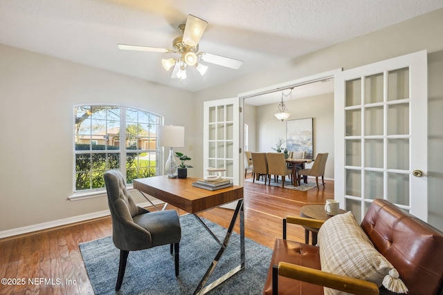 home office featuring ceiling fan, wood-type flooring, a textured ceiling, and french doors