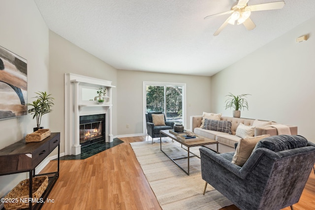 living room featuring ceiling fan, light hardwood / wood-style floors, and a textured ceiling