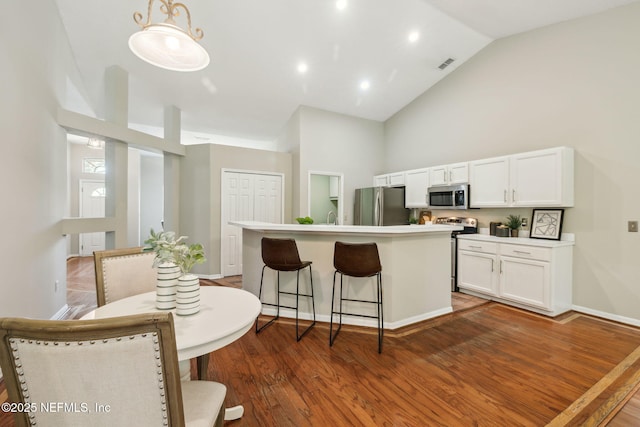 kitchen with pendant lighting, a breakfast bar, a center island, white cabinets, and appliances with stainless steel finishes