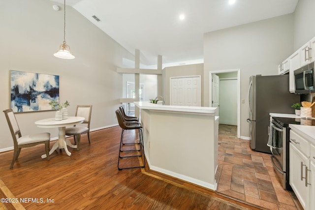 kitchen featuring white cabinetry, an island with sink, hanging light fixtures, and appliances with stainless steel finishes