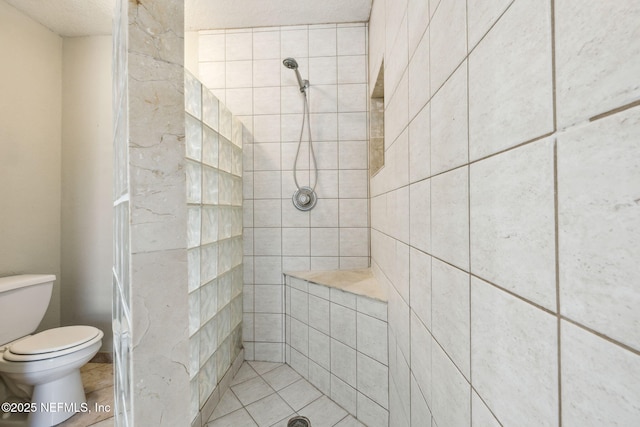 bathroom featuring a textured ceiling, toilet, and tiled shower