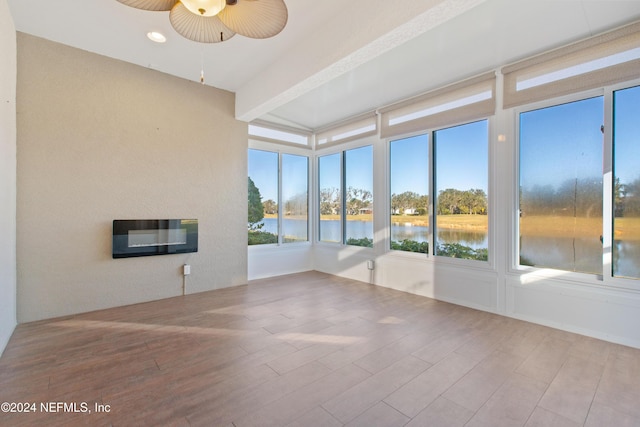 unfurnished sunroom with a water view, heating unit, and ceiling fan