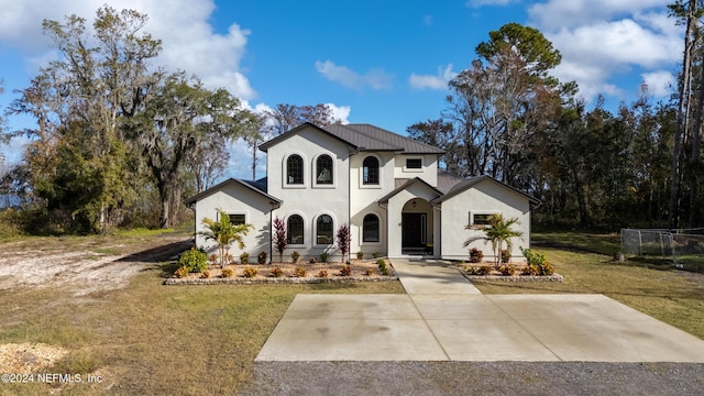 view of front of property with stucco siding, concrete driveway, and a front yard