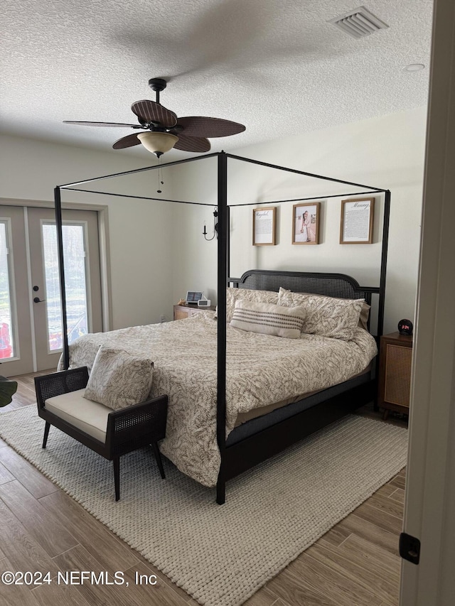 bedroom featuring hardwood / wood-style flooring, ceiling fan, and a textured ceiling