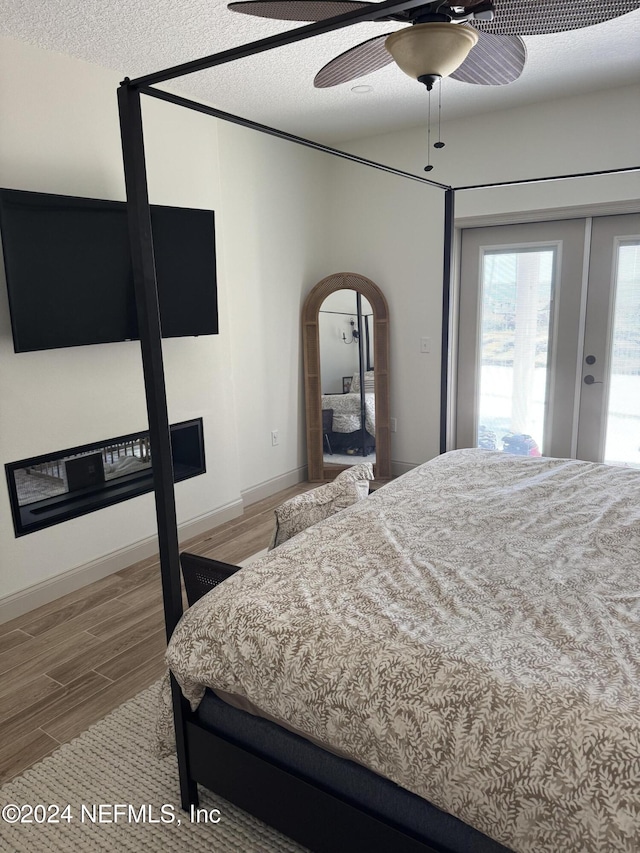 bedroom featuring hardwood / wood-style flooring, ceiling fan, access to exterior, and a textured ceiling