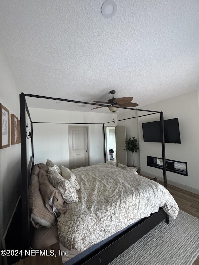 bedroom featuring ceiling fan, wood-type flooring, and a textured ceiling