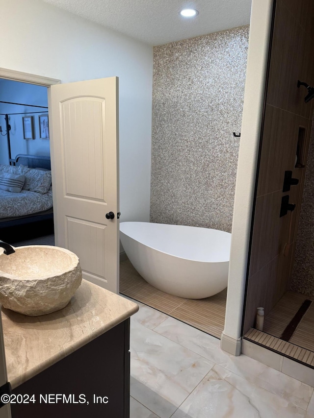 bathroom with vanity, independent shower and bath, and a textured ceiling