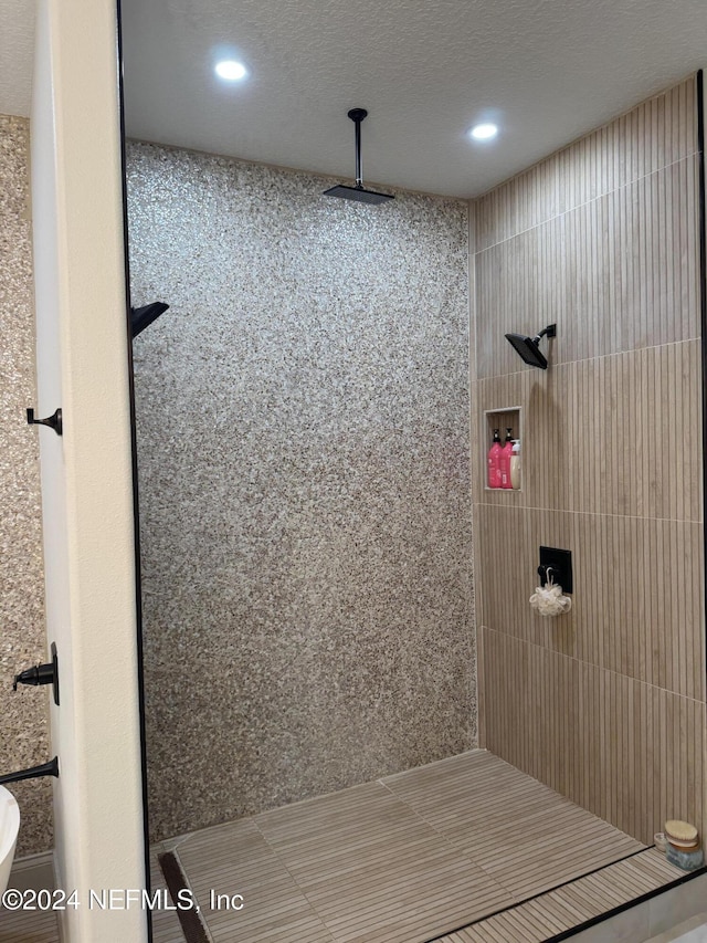 bathroom with a textured ceiling and tiled shower