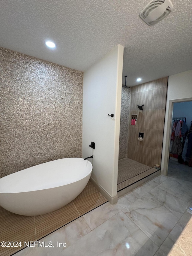 bathroom featuring shower with separate bathtub and a textured ceiling