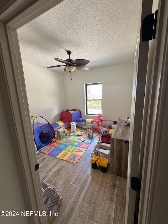 rec room featuring hardwood / wood-style floors, a textured ceiling, and ceiling fan