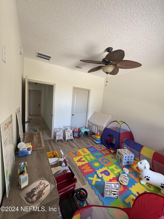 bedroom featuring dark hardwood / wood-style floors, ceiling fan, and a textured ceiling