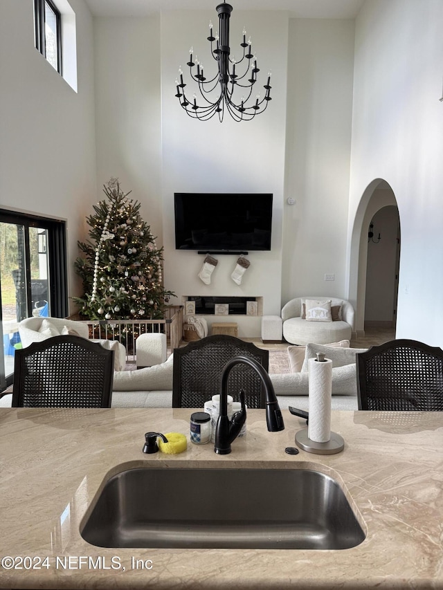 living room featuring a high ceiling, an inviting chandelier, a healthy amount of sunlight, and sink