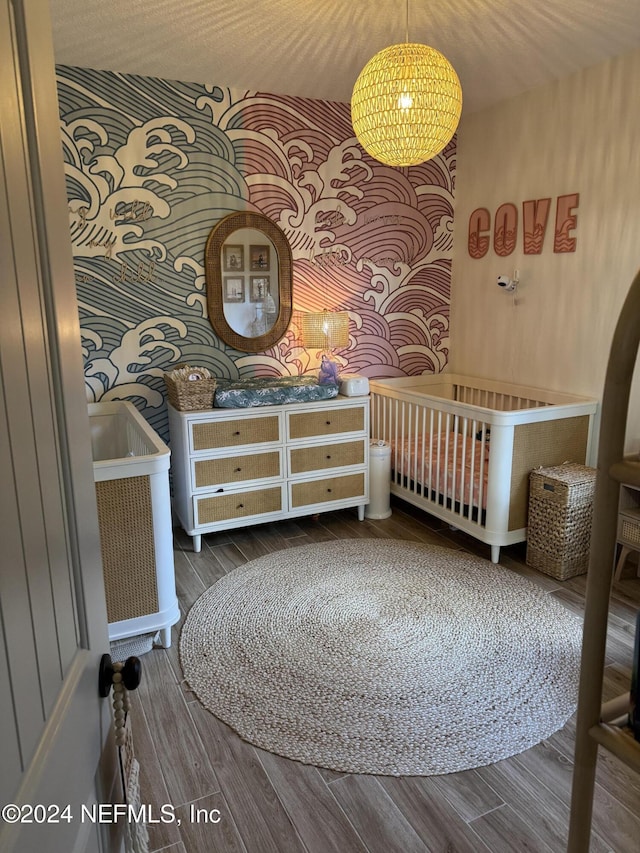 bedroom featuring hardwood / wood-style floors and a nursery area