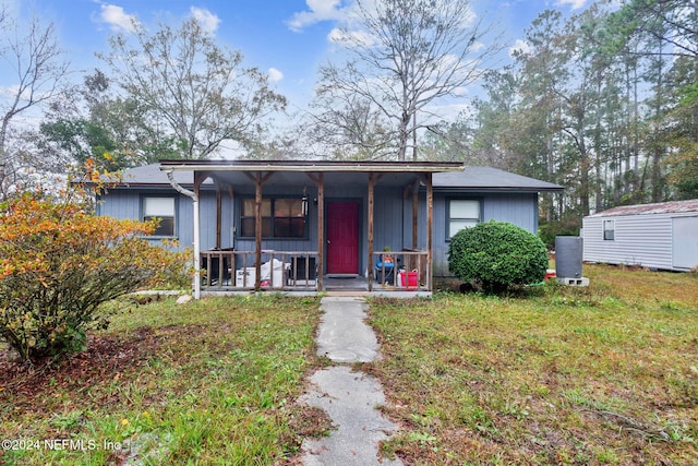 view of front facade with a storage unit, a porch, and a front lawn