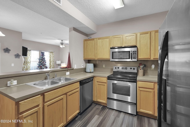 kitchen with dark wood-type flooring, sink, a textured ceiling, kitchen peninsula, and stainless steel appliances