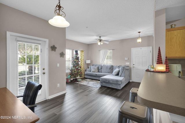 living room featuring dark hardwood / wood-style flooring, ceiling fan, and a healthy amount of sunlight