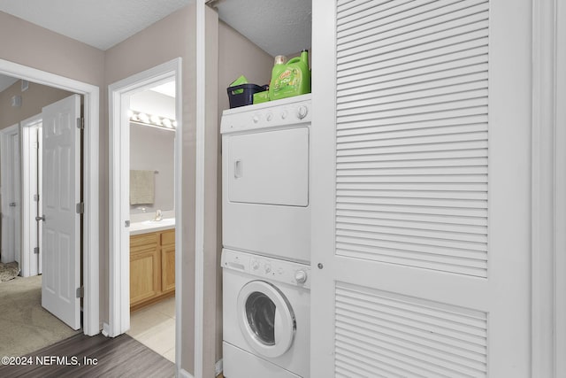 washroom featuring a textured ceiling, sink, dark hardwood / wood-style flooring, and stacked washer and dryer