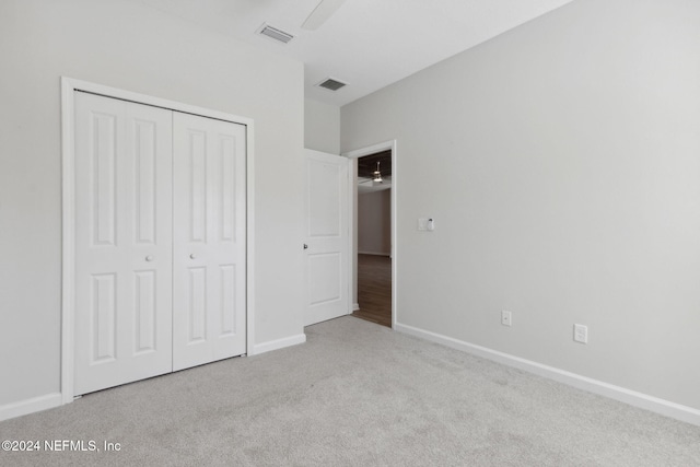 unfurnished bedroom featuring ceiling fan, light colored carpet, and a closet