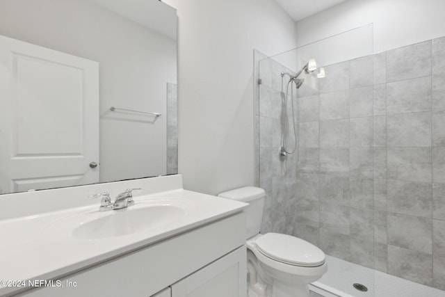 bathroom with a tile shower, vanity, and toilet